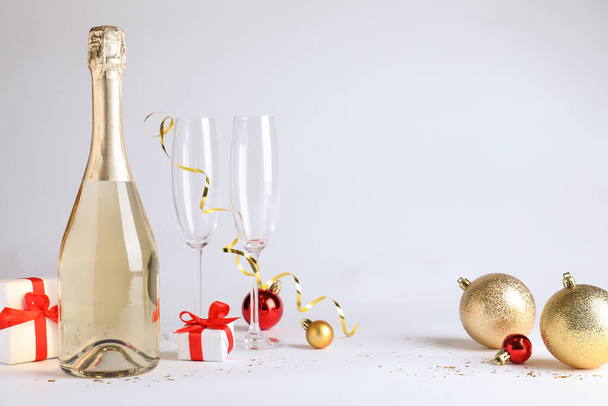 Happy New Year! Bottle of sparkling wine, glasses and festive decor on white background - Photo, image