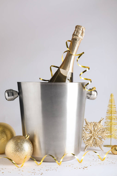 Happy New Year! Bottle of sparkling wine in bucket and festive decor on white background - Fotoğraf, Görsel