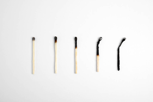 Different stages of burnt matches on white background, flat lay - Фото, зображення