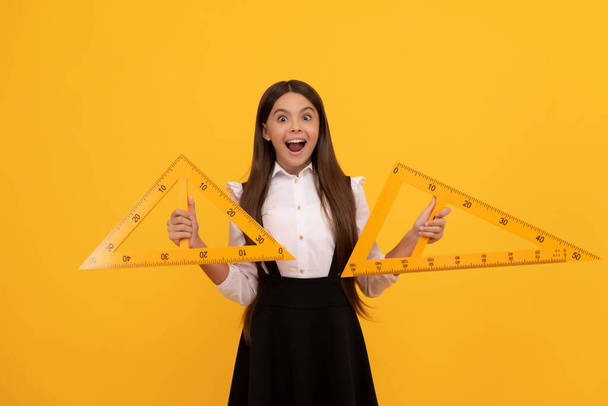 surpris enfant en uniforme scolaire tenir triangle mathématiques pour la mesure, la connaissance - Photo, image