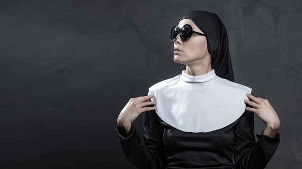 Beautiful woman wearing nun costume and halloween makeup over dark gray background - Foto, immagini