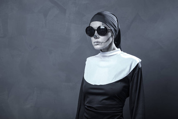 Beautiful woman wearing nun costume and halloween makeup over dark gray background - Fotoğraf, Görsel