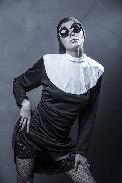 Beautiful woman wearing nun costume and halloween makeup over dark gray background - Foto, Bild