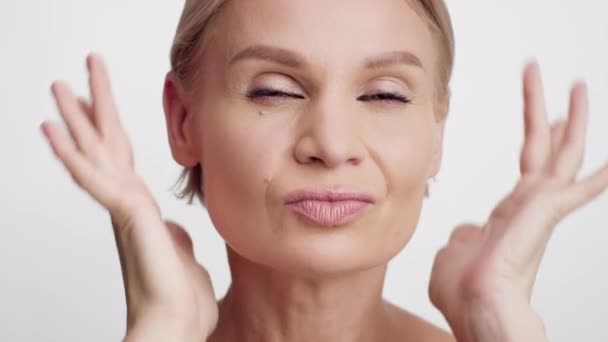 Concepto de lifting facial. Hermosa mujer de mediana edad haciendo masaje facial revitalizante - Metraje, vídeo