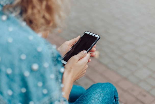 女性の手は屋外のデバイスの画面を見て、夏の公園でスマートフォンを使用しています - 写真・画像