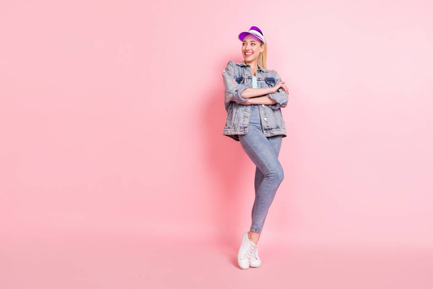 Full body photo of lovely millennial sporty lady look empty space wear jeans shirt cap isolated on pink color background - Photo, Image