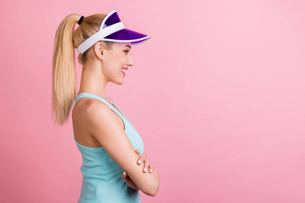 Фотографія профілю оптимістичного хвіст зачіски молода спортивна леді схрещеними руками виглядає вдягненим капелюхом бірюзовий топ ізольовано на рожевому кольоровому фоні
 - Фото, зображення