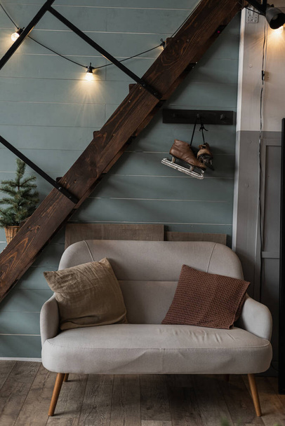 Moderno escandinavo hygge estilo hogar sala de estar diseño interior. Cómodo y acogedor sofá, con almohadas, luces de guirnalda brillante, escaleras, pared azul. Elegante Navidad, decoraciones de celebración de Año Nuevo - Foto, Imagen