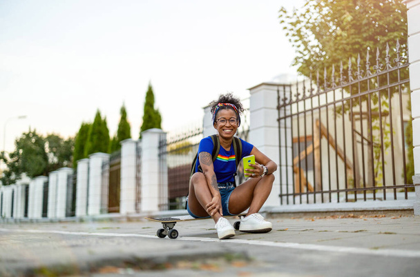Young woman sitting on skateboard in the city - Φωτογραφία, εικόνα