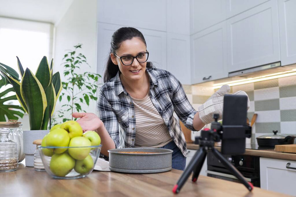 Weibliche Aufzeichnung eines Apfelkuchenrezepts auf dem Smartphone zu Hause in der Küche - Foto, Bild