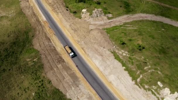 Εναέρια άποψη βαριά εξόρυξη τεσσάρων αξόνων λευκό χωματερή φορτηγών χύνει άμμο από το σώμα για την κατασκευή νέου ασφαλτοστρωμένου δρόμου - Πλάνα, βίντεο