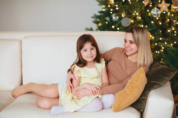 Glücklich verspieltes kleines Mädchen Tochter spielt mit positiver Mutter, verbringen Zeit zusammen in den Weihnachtsferien zu Hause, Mutter und Kind haben Spaß im Wohnzimmer mit Silvesterbaum - Foto, Bild