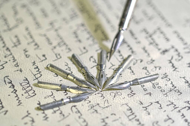 Fémfalatok és régi tollak közelsége régi kézírással. Töltőtoll egy ősi, kézzel írott levélen. Régi történet. Retro stílus - Fotó, kép