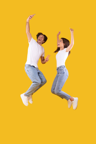 Aufgeregtes Millennial-Paar macht Selfie und springt im Studio - Foto, Bild