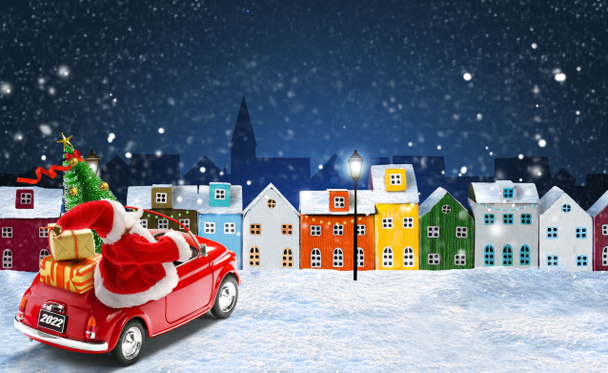 Joulutervehdyskortti. Joulupukki ajaa punainen auto lahjapakkauksia ja joulukuusi yöllä joulu kaupunki - Valokuva, kuva