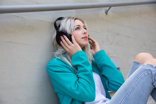 mladá blondýna žena chlazení a těší hudbu se sluchátky - Fotografie, Obrázek