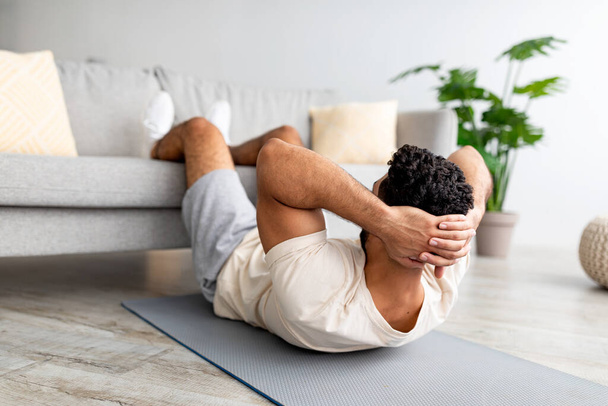 Подходит молодой арабский парень, тренирующий мышцы абса на коврике для йоги дома. Концепция фитнеса - Фото, изображение