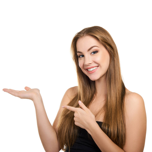 Young attractive woman with perfect make-up and long fair hair smiling and pointing with her hands at copy space at studio over white background, beauty female portrait.  - Φωτογραφία, εικόνα