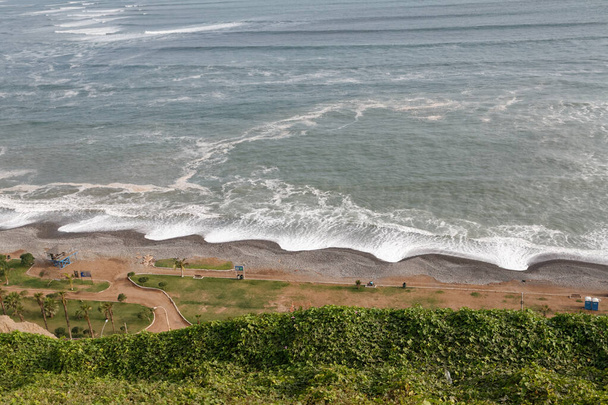 Costa do Pacífico em Lima, Peru, uma vista do penhasco íngreme sobre as ondas que se aproximam. - Foto, Imagem