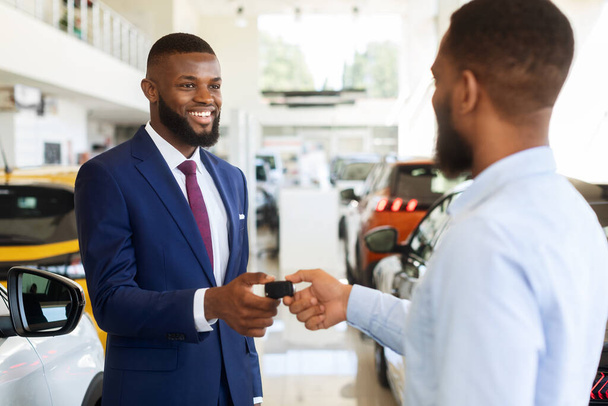 Autoverkauf oder Miete. Schwarzer Manager übergibt Schlüssel an männlichen Kunden, Nahaufnahme - Foto, Bild