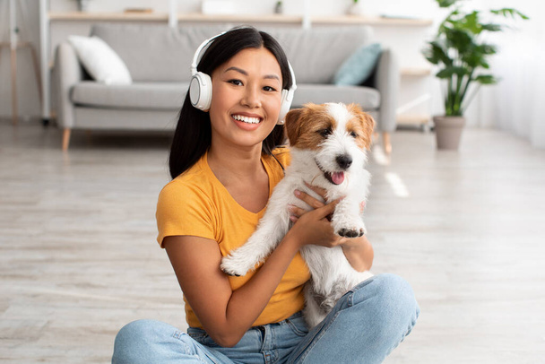 Pretty asian woman resting with her pet at home - Фото, изображение
