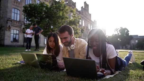 Jóvenes estudiantes que usan computadoras portátiles durante el estudio al aire libre - Imágenes, Vídeo