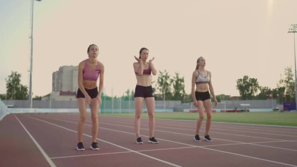 3 coureuses se préparent pour la course longue distance au stade au coucher du soleil au ralenti - Séquence, vidéo