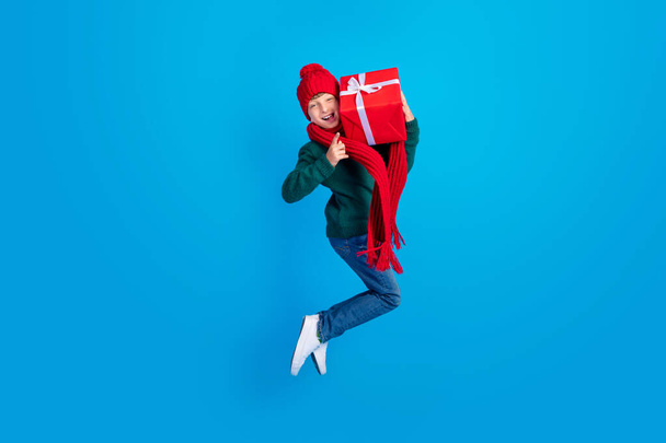 Full length body size photo boy jumping keeping xmas present showing horns isolated bright blue color background - 写真・画像