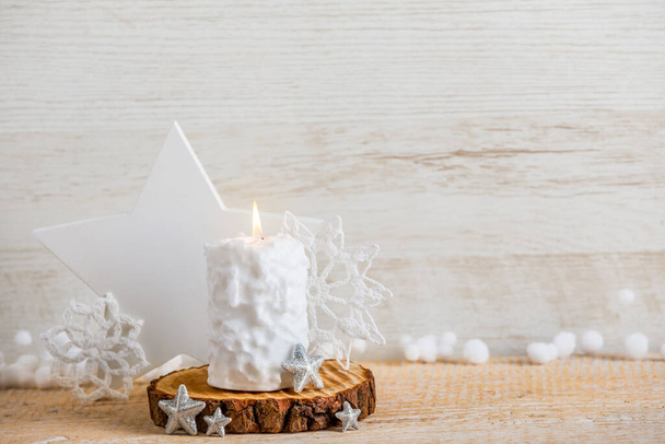 Vintage estilo nórdico minimalista fondo de Navidad con un montón de espacio de copia. Enfoque selectivo en el patrón de bola de nieve vela blanca quema, decoraciones de forma de estrella para la decoración sobre fondo de madera. - Foto, imagen
