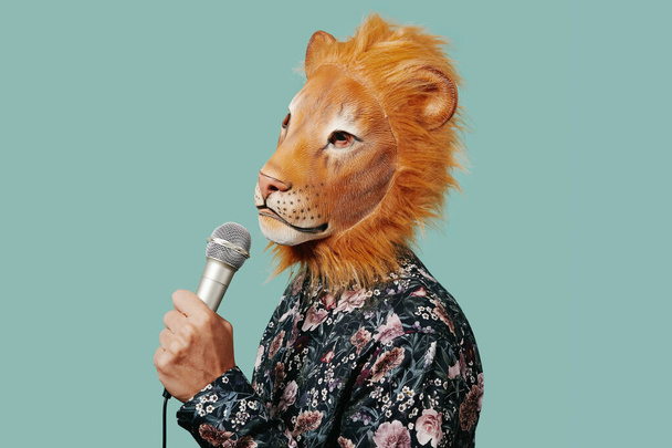 detailní záběr mladého muže s maskou lva pomocí mikrofonu na modrém pozadí s prázdným prostorem kolem - Fotografie, Obrázek
