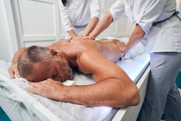 Чоловік отримує терапевтичний масаж спини в оздоровчому центрі
 - Фото, зображення