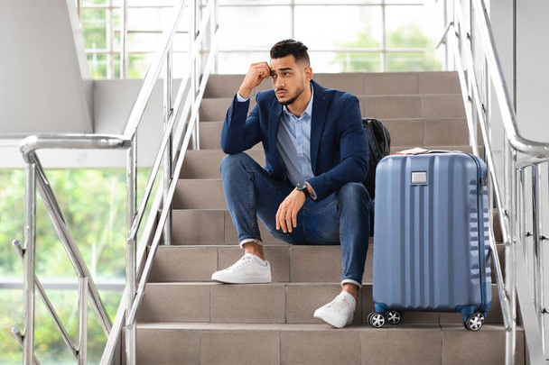 Cancellazione del volo. Uomo arabo sconvolto seduto con i bagagli alle scale in aeroporto - Foto, immagini