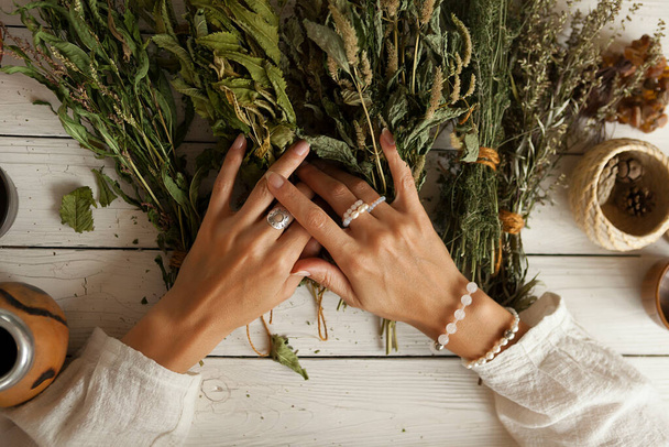  bunch of dried medicinal herbs in women's hands,  collection of medicinal herbs, white wooden table - Foto, immagini