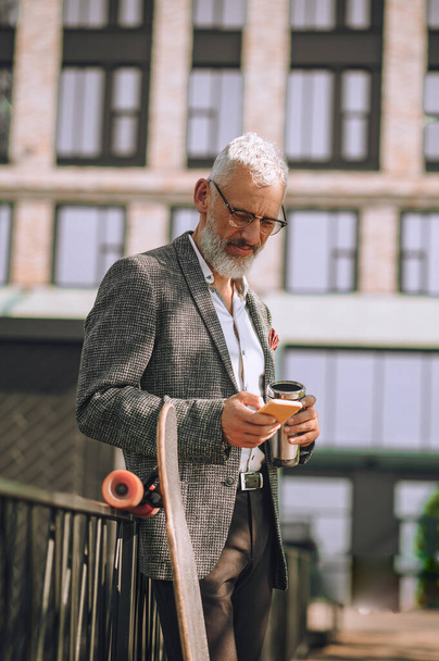 Um homem de cabelos grisalhos com um gadget nas mãos - Foto, Imagem