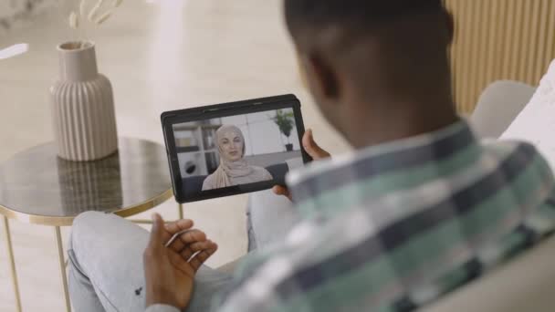 Tablet pc screen with Muslim woman in hijab, talking with her African male friend via online video chat - Záběry, video