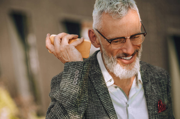 Egy ősz hajú férfi szemüvegben, aki hangüzenetet hallgat. - Fotó, kép