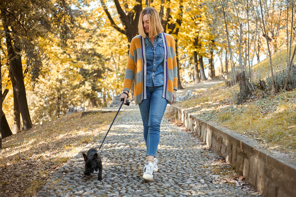  happy young woman walking with French Bulldog outdoors in autumn - Photo, image
