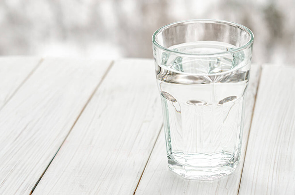 Un vaso con agua limpia y clara. Vaso de agua con medio agua llena sobre la mesa, concepto de pensamiento positivo y negativo - Foto, Imagen