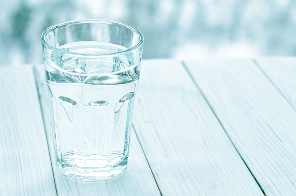 Een glas met schoon helder water. Glas water met half vol water op tafel, concept van positief en negatief denken - Foto, afbeelding
