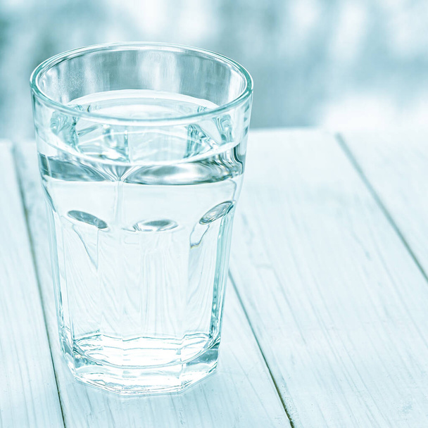 Un bicchiere con acqua pulita e limpida. Bicchiere d'acqua con mezza piena d'acqua sul tavolo, concetto di pensiero positivo e negativo - Foto, immagini