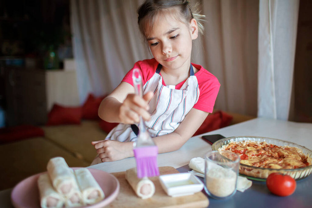 Dívka vaření klobása rolované v phyllo pečivo k snídani, malý kuchař má chutnou svačinu - Fotografie, Obrázek