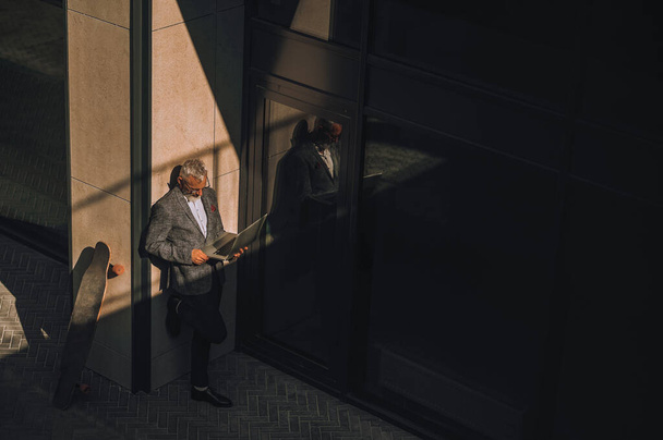A gray-haired man standing near the wallnear the office building - Valokuva, kuva