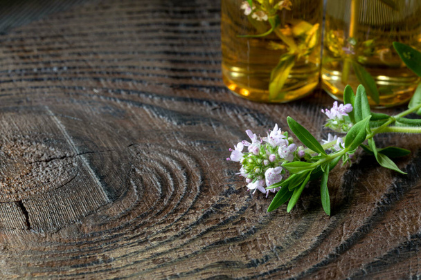 Egy virágzó kakukkfű és egy üveg illóolaj sötét fából készült háttéren, a szöveg helyének másolatával. Az alternatív gyógyászat háttere. - Fotó, kép