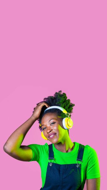Joven cabello rizado mujer negra aislada bailando escuchando música con auriculares inalámbricos - Foto, imagen
