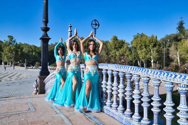 Açık mavi giyinmiş üç güzel dansçı şehir meydanında dans ediyor. Göbek dansı ve göbek dansı konsepti, Afrika folkloru.. - Fotoğraf, Görsel