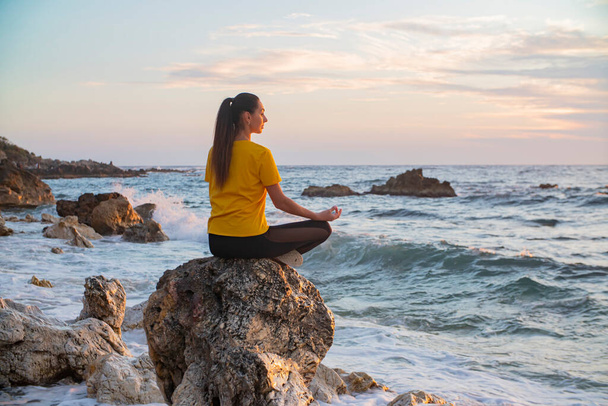 Yoga woman in Lotus position practicing yoga and meditation. outdoors on the evening ocean - Photo, Image