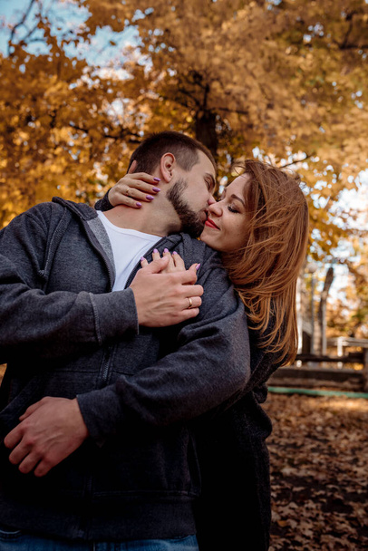 Beautiful young couple man and woman hugging in the park near the pond in leaf fall in autumn - Fotoğraf, Görsel