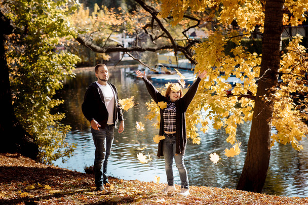 Young people man and woman throw up autumn leaves in autumn in the park during leaf fall - Фото, зображення