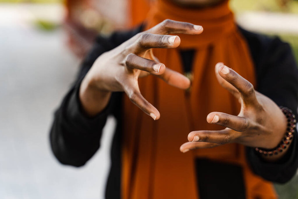 Крупным планом руки черной мусульманки на цигун китайской медитации и спортивной подготовки на открытом воздухе. Африканская девушка медитирует на открытом воздухе возле китайской беседки - Фото, изображение