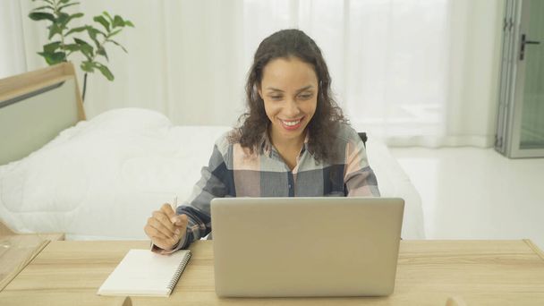 Relax gelukkige latin jonge zakenvrouw werken vanuit huis. Mensen typen op computer laptop notebook apparaat en het schrijven van een boek. social media internet technologie met een bed in de slaapkamer thuis. Levensstijl - Foto, afbeelding